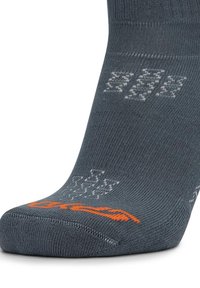Calcetín gris oscuro con un logo naranja en la punta y patrones anti-deslizantes de textura gris claro en la parte superior y en el talón.