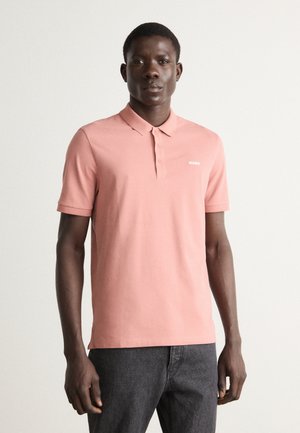 Polo rose clair en coton avec un col, trois boutons et un petit logo blanc « HUGO » sur la poitrine gauche.