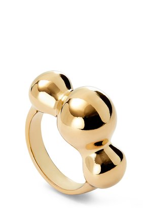 Anillo de oro con tres esferas redondeadas conectadas como elemento decorativo central sobre un fondo blanco.