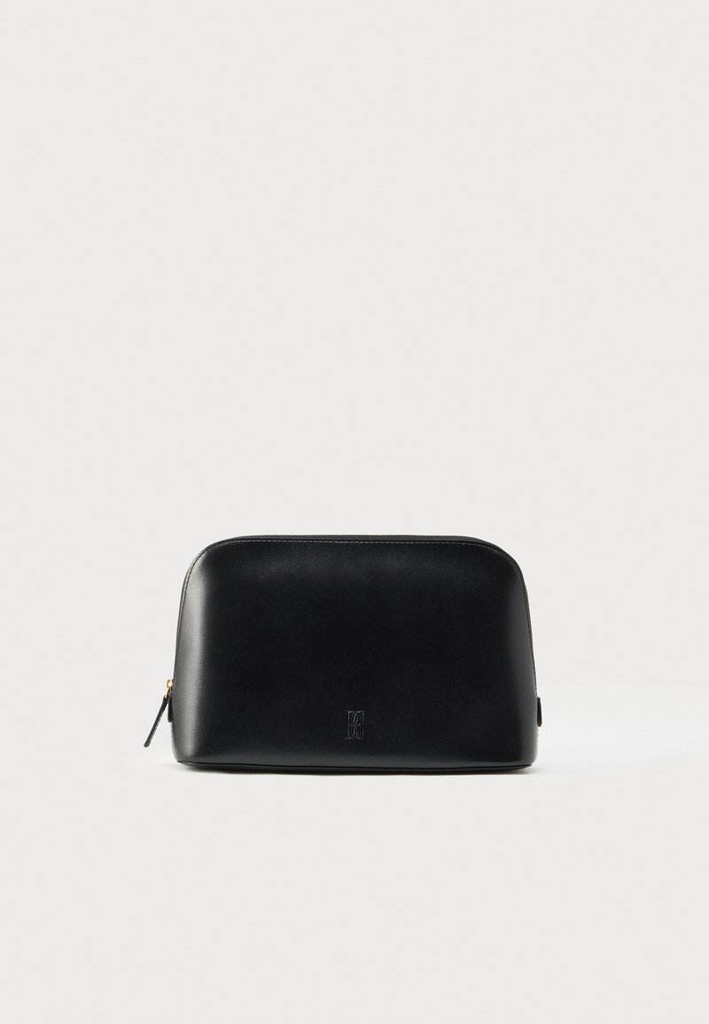 Black leather pouch with a smooth texture, rounded shape, and tonal logo on the front. Features a zippered closure and gold hardware accent.