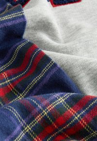 Sweter z dzianiny o szarym tle w kratę w kolorze granatowym, z akcentami w kolorze czerwonym, żółtym i purpurowym, ukazujący miękką teksturę.