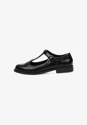 Zapato T-bar de cuero negro con detalles perforados, puntera redonda y correa con hebilla. Suela plana con tacón bajo. Textura suave.
