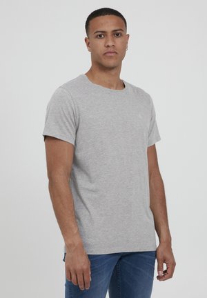 Grå bomulds T-shirt med rund hals og korte ærmer. Har et diskret logo på brystet. Stylet med blå jeans.