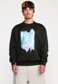 Sweatshirt noir en mélange de coton avec un design abstrait holographique sur le devant. Poignets et taille côtelés pour un ajustement confortable.