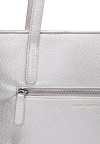Sac fourre-tout en cuir texturé blanc avec une fermeture zippée sur le dessus, quincaillerie en argent et une poche avant avec un logo discret.