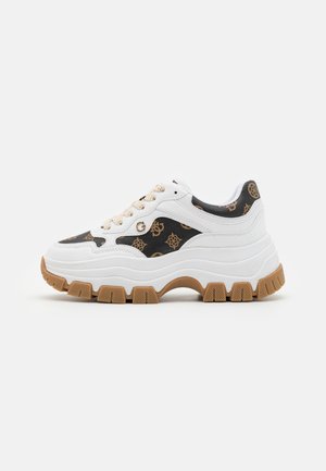 Zapatilla blanca gruesa con paneles de tela marrones con estampado, cordones beige, logotipo dorado "G" y suela gruesa de goma color marrón claro con ranuras profundas.