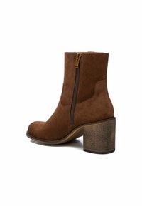 Stivale alla caviglia in suede marrone con cerniera laterale, punta rotonda e tacco in legno spesso. Presenta una texture liscia e un design pulito.