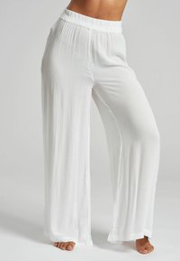 Pantalones blancos de pierna ancha hechos de una tela ligera con un acabado texturizado. Presentan una cintura elástica y una silueta fluida.