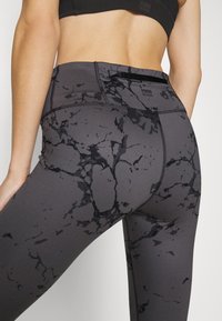 Black marble-patterned leggings featuring a high waistband, seamless design, and a small pocket near the waist. Made of stretchy material.