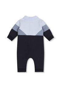 Une combinaison tricotée rayée bleu marine et bleu clair avec un col, présentant un tissu texturé et des manches longues. Conception à jambes ouvertes.