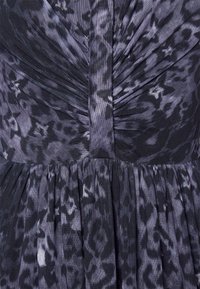 Lila und schwarze gemusterte Stoff mit einem gerafften Oberteil und einem gerafften Rockdetail. Weiche Textur, mittleres Gewicht und fließendes Design.