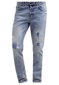 Hellblaue Jeans aus Denim mit abgetragenen Stellen an beiden Oberschenkeln und verstärktem Stoff, der unter den Rissen sichtbar ist, Fünf-Taschen-Stil, gerade Passform.
