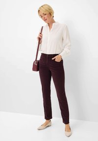 Witte button-up shirt, bordeauxkleurige broek en beige ballerina's. Eenvoudig ontwerp, gladde textuur en een klein crossbody tasje. Schone, moderne uitstraling.