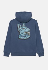 Blå huvtröja med en texturerad grafik av ett stiliserat hundhuvud på baksidan. Tillverkad av mjuk textil med dragsko i huvan och ribbade muddar.