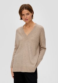 Beige v-hals gebreide trui, met een relaxed fit, ribgebreide manchetten en zijsplitten. Zachte textuur met een gladde afwerking.