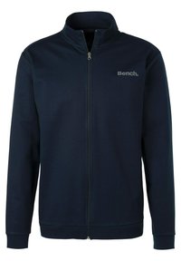 Navy blauwe zip-up jack gemaakt van zacht materiaal. Heeft een hoge kraag, lange mouwen en een subtiele "Bench." logo op de borst.