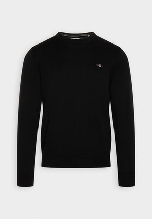 Black cotton sweater with a round neckline, long sleeves, ribbed cuffs and hem, featuring a small logo on the chest. Classic fit.
