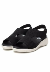 Sandalias negras con una parte superior texturizada y trenzada, punta abierta y correas elásticas. Cuentan con una suela de goma blanca para mayor comodidad y soporte.
