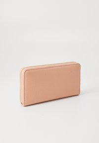 Portefeuille en cuir pêche avec une surface texturée, de forme rectangulaire et fermeture éclair dorée. La fermeture éclair s'étend sur le dessus et le côté pour un accès facile.