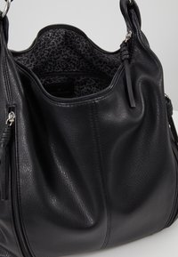 Černá kožená kabelka s zipovým otvorem na vrchu, podšívkou s leopardím vzorem a dvojitými držadly.