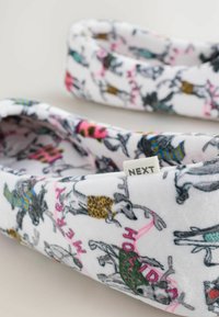 Fleece-tofflor med en vit bakgrund som har ett färgglatt hundtryck. Inkluderar 'NEXT'-etiketten och detaljer i rosa, grönt och leopardmönster.