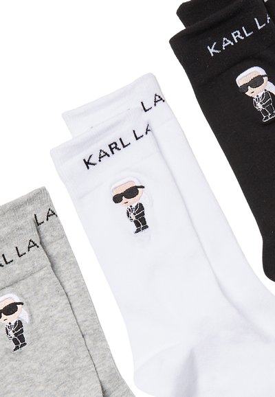 Chaussettes blanches, grises et noires avec un design de personnage de dessin animé portant des lunettes de soleil et un costume. Logo "KARL LAGERFELD" sur le revers de chaque chaussette.
