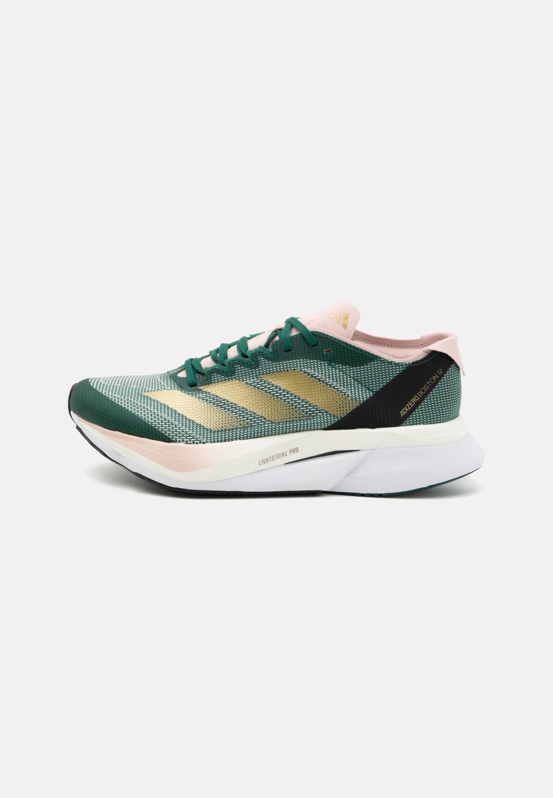 Zielony i czarny but do biegania z siatkową cholewką, złotymi paskami i różowymi akcentami. Posiada lekką podeszwę oznaczoną napisem "LIGHTSTRIKE PRO".