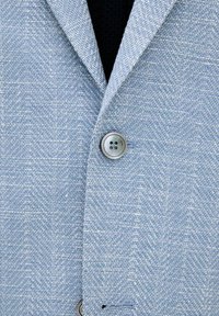 Blazer azzurro chiaro con motivo a spina di pesce, rever a punte e chiusura a un bottone. Il tessuto ha una finitura texture.