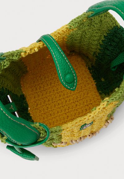 Πλεκτή τσάντα χειρός με πράσινο και κίτρινο νήμα, με υφή στο εσωτερικό και πράσινους δερμάτινους ιμάντες με ασημί εξαρτήματα.