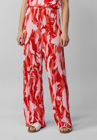 Pantaloni morbidi e plissettati di colore rosso con motivi astratti bianchi. Presentano un elastico in vita e gambe ampie, realizzati in tessuto leggero.