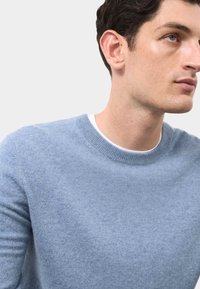 Jasnoniebieski sweter z okrągłym dekoltem, wykonany z miękkiego materiału, z ribbowanym kołnierzem i bezszwowym zamkiem ramion, charakteryzujący się gładką teksturą i klasycznym stylem.