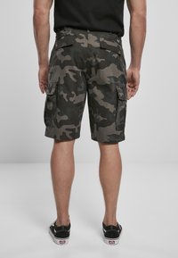 Cargo shorts in een donker camouflagepatroon. Gemaakt van stof met een gestructureerde afwerking. Beschikt over meerdere zijzakken en een omgeslagen zoom.
