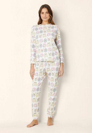 Ensemble de pyjama deux pièces avec un fond blanc et des motifs animaliers colorés ; tissu doux, manches longues et taille élastique sur le pantalon.
