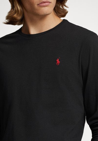 Svart langermet T-skjorte i bomull med rund hals og en liten rød brodert logo på brystet. Jevn tekstur.