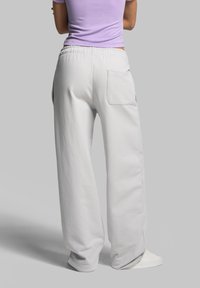 Hellgraue Jogginghose mit lockerer Passform, elastischem Bund und einer Gesäßtasche. Weiche Textur mit weitem Bein-Design. Minimalistischer Stil.