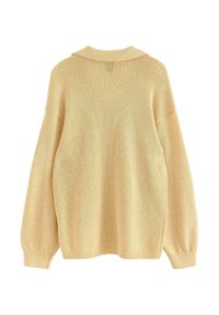 Lys gul strikket sweater med en afslappet pasform, ribbet kant og oversized ærmer. Bagsiden har et diskret struktureret mønster.