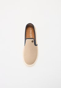 Chaussure beige en toile à enfiler avec un contour bleu marine, bout arrondi et semelle en liège. Présente un petit logo sur le côté et une surface supérieure texturée. Taille 42.