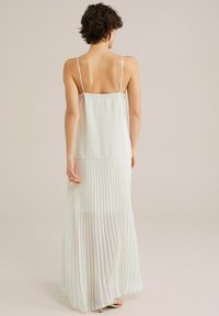 Maxikleid mit dünnen Trägern, aus leichtem, weichem Stoff. Besitzt ein einfarbiges Oberteil und einen plissierten, durchsichtigen Rock in einem hellen Minzgrün.