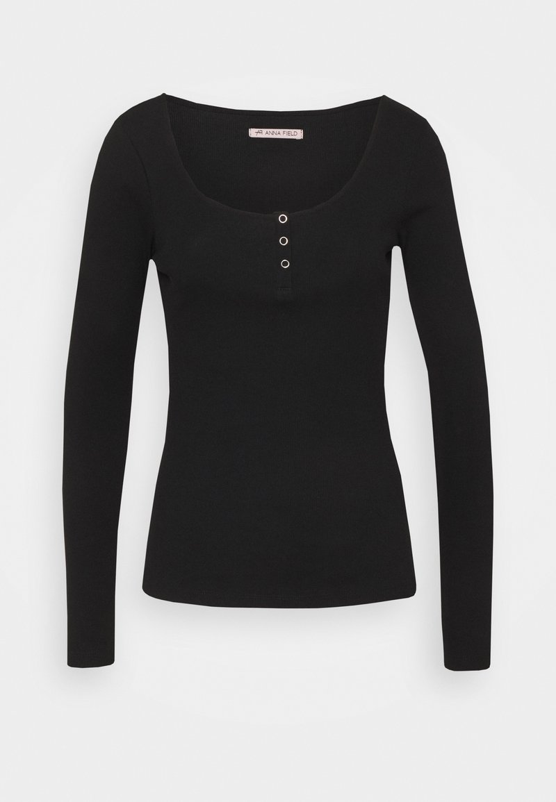Schwarzes Langarmshirt mit Rundhalsausschnitt, das an der Vorderseite drei Druckknöpfe aus Metall aufweist. Hergestellt aus dehnbarem Stoff mit glatter Textur.