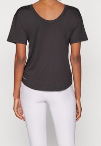 Svart t-shirt med korta ärmar och rundad halsringning, slät textur och något böjd fåll, sedd bakifrån.