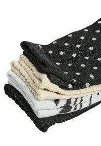 Zestaw pięciu par teksturowanych skarpet w różnych kolorach: czarne w białe kropki, beżowe, kremowe oraz czarne z graficznymi paskami.