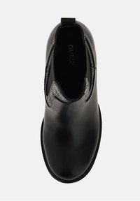 Musta nahkasaapas nilkkapituudella, joustavilla sivupaneeleilla, pyöreällä varvalla ja teksturoidulla kuviolla nilkassa. Huomaamaton brändäys sisäpuolella.