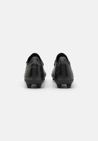 Scarpe da calcio nere con superficie testurizzata, tacchi arrotondati e tacchetti stampati sulla suola, viste da dietro.