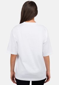 Maglietta bianca in cotone con collo a giro, maniche corte e vestibilità rilassata; texture liscia, senza motivi o dettagli visibili sul retro.