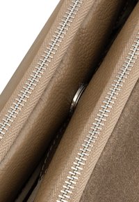 Tan leren portemonnee met een ritsluiting, voorzien van een gladde textuur, zichtbare compartimenten en een zilveren rits voor veilige sluiting.