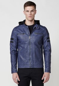 Chaqueta de cuero sintético azul con cierre frontal, acentos en los hombros, dos bolsillos en el pecho y detalles a rayas negras en las mangas. Diseño con capucha.