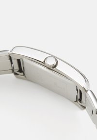 Cercei de argint cu un carcas metalică netedă, coroana rotundă și un design plat. Are un finisaj lustruit și o conexiune a brățării fără sudură.