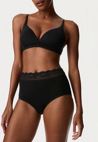 Černá podprsenka s měkkými, tvarovanými košíčky a tenkými nastavitelnými ramínky, doplněná černými kalhotkami s vysokým pasem a krajkovým lemováním.