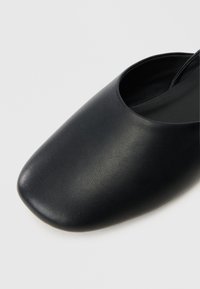 Czarne skórzane buty wsuwane z wąskim, zaokrąglonym noskiem i gładką fakturą; minimalistyczny design bez widocznych elementów metalowych ani zdobień.