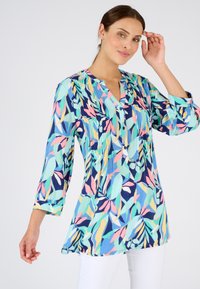 Blusa de manga larga en tela ligera con base azul y patrones de hojas coloridos en verde, rosa y amarillo. Cuello con botones.
